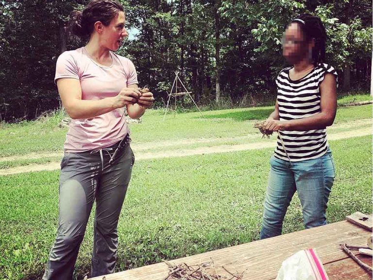 Laura training student in friction fire beginning with cedar bark tinder